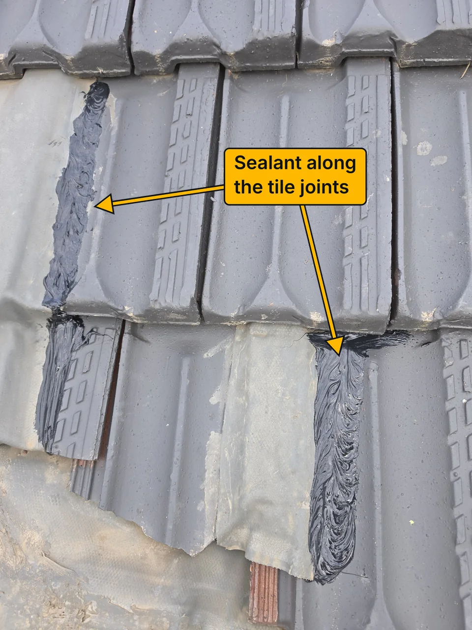 Roof tiles after the repair, with fresh black sealant applied along the tile joints. A label with arrows points to the sealed joints.