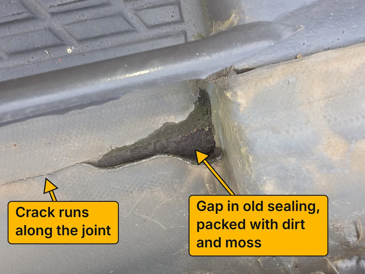 Another view of the damaged flashing before the repair. Labels point to a gap in the old sealing packed with dirt and moss, and to a crack running along the joint.